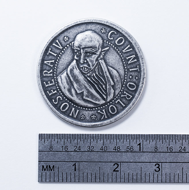 Silver Nosferatu coin depicting Max Schreck's likeness as Count Olaf in F. W. Murnau's 1922 film, Nosferatu, photographed alongside a ruler to demonstrate its length , 1.5 inches