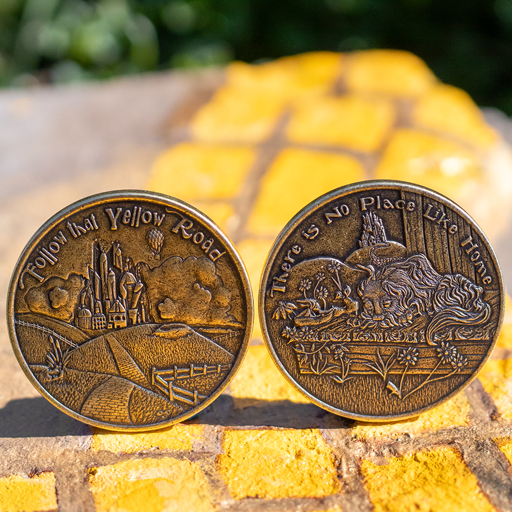 Two brass Dorothy's Decision Maker coins displayed on hand painted yellow brick road