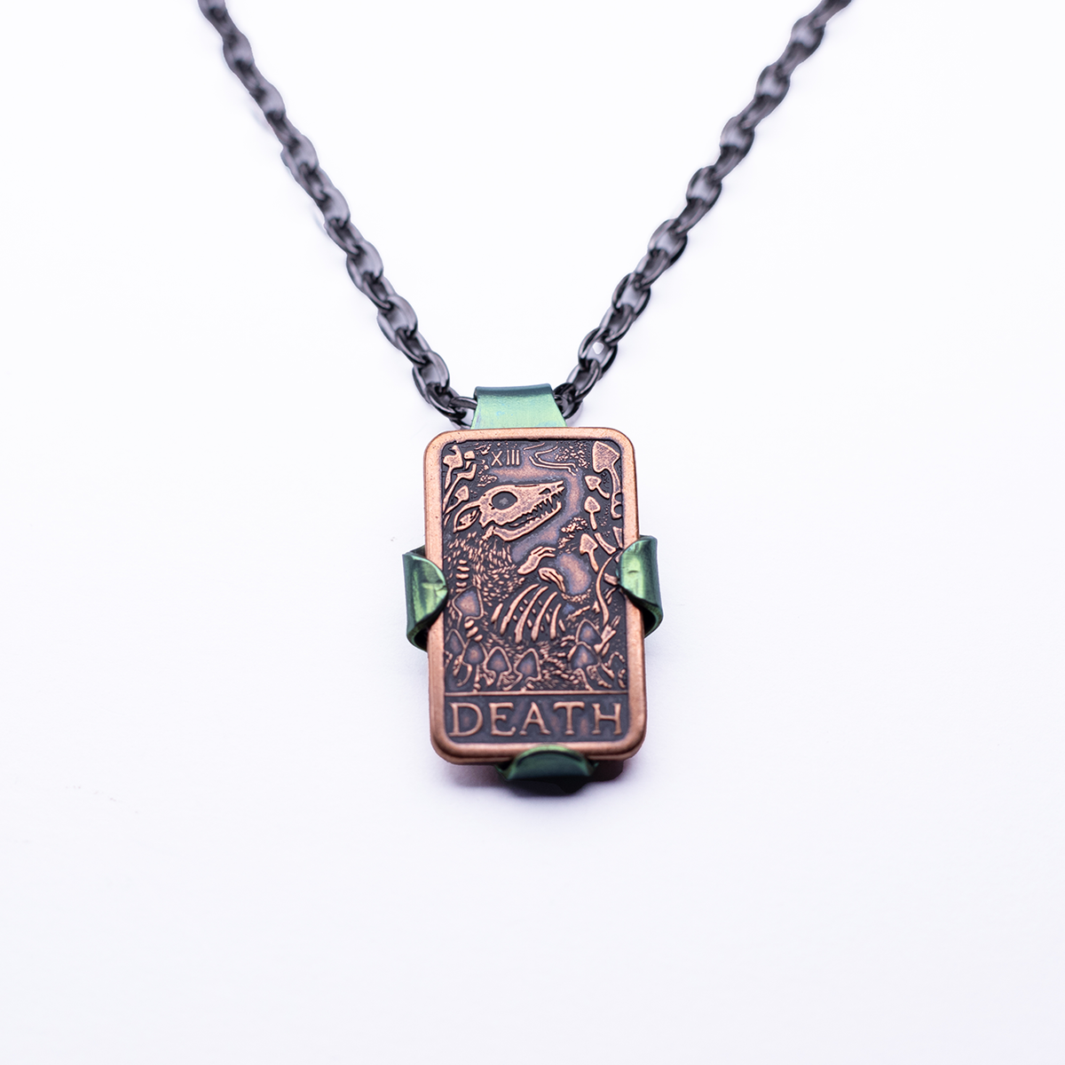 Leaf-shaped niobium green holder pendant clasping a copper Tarot Death Coin against a white background.