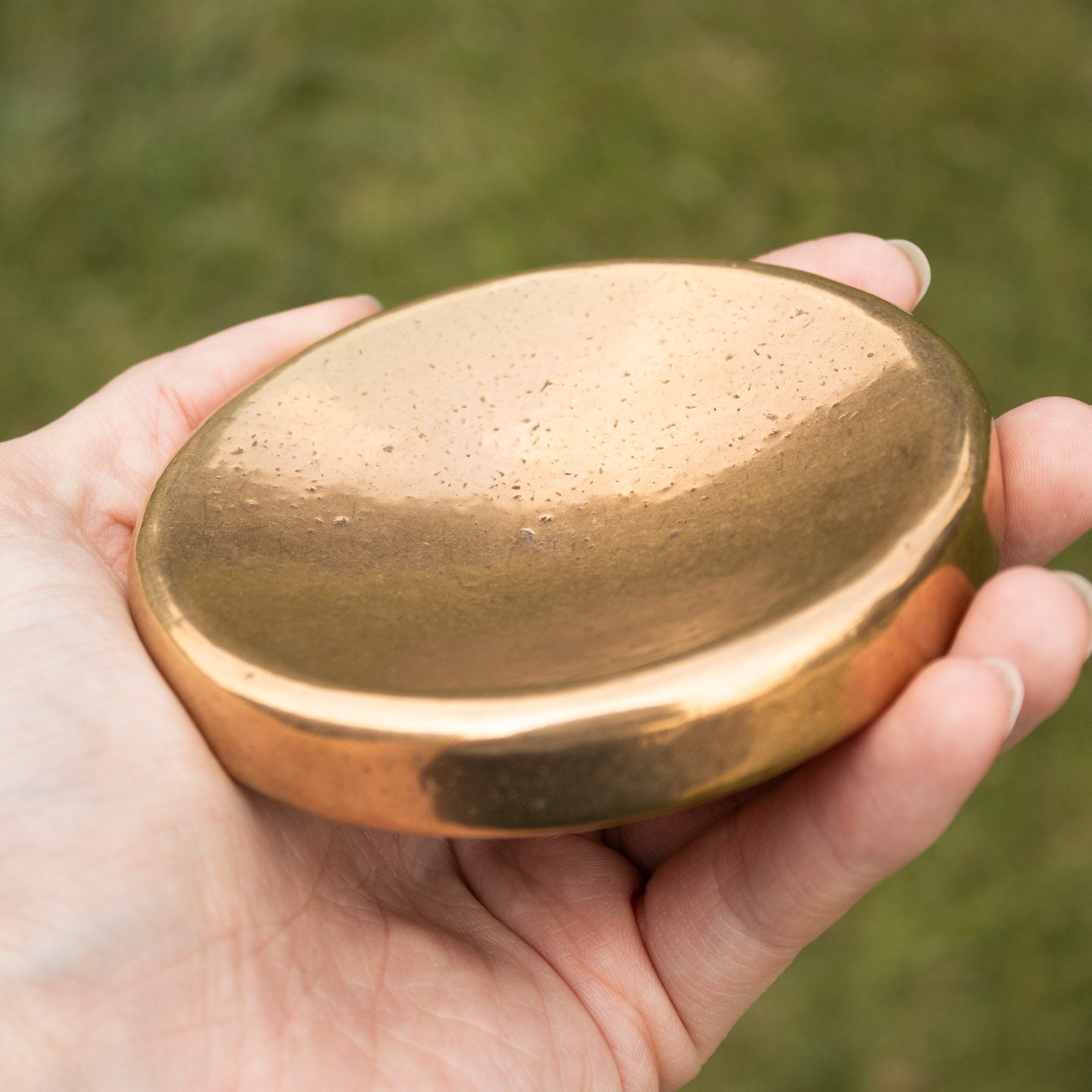 A bronze bowl held in the hand outdoors