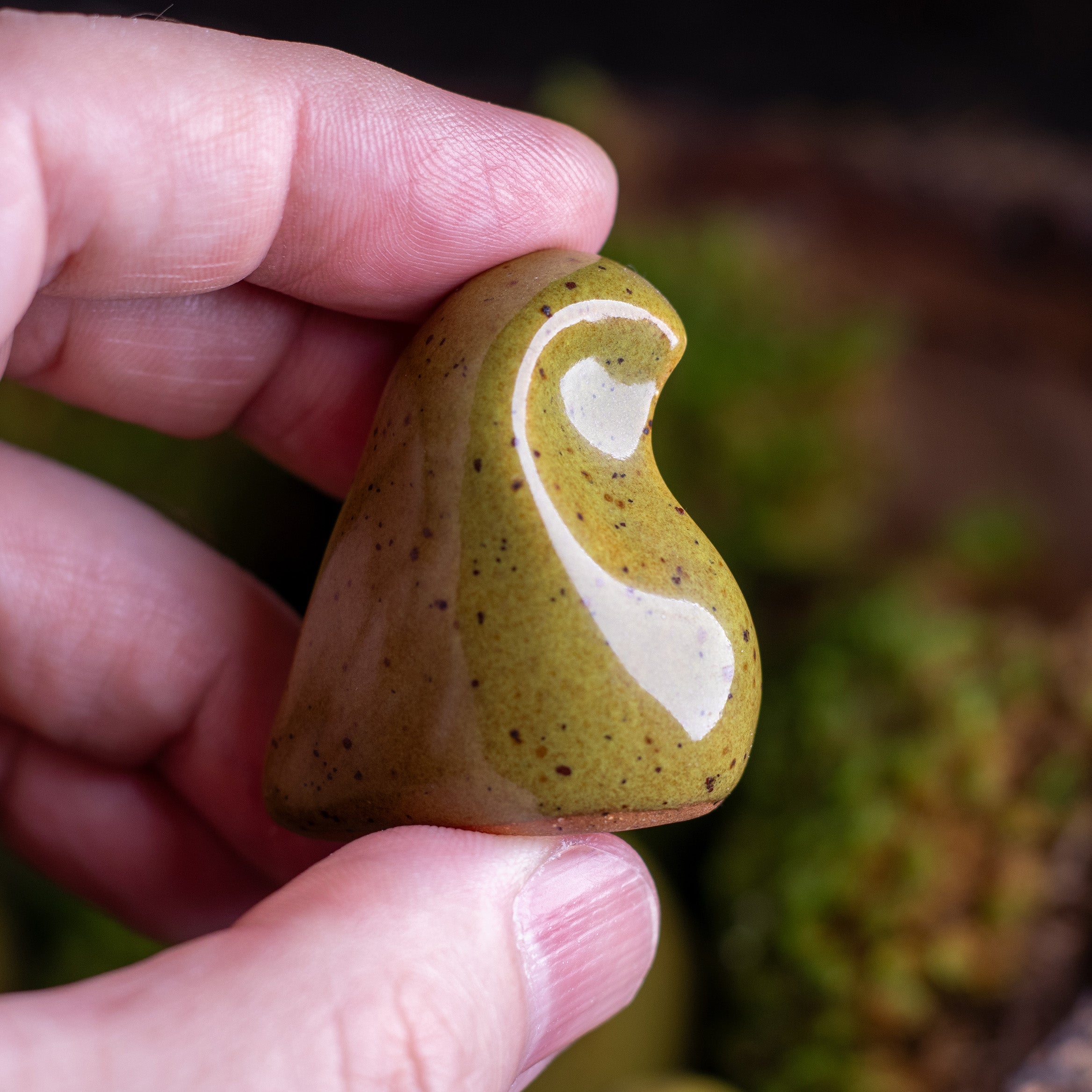 Hand holding earthenware green worry finch