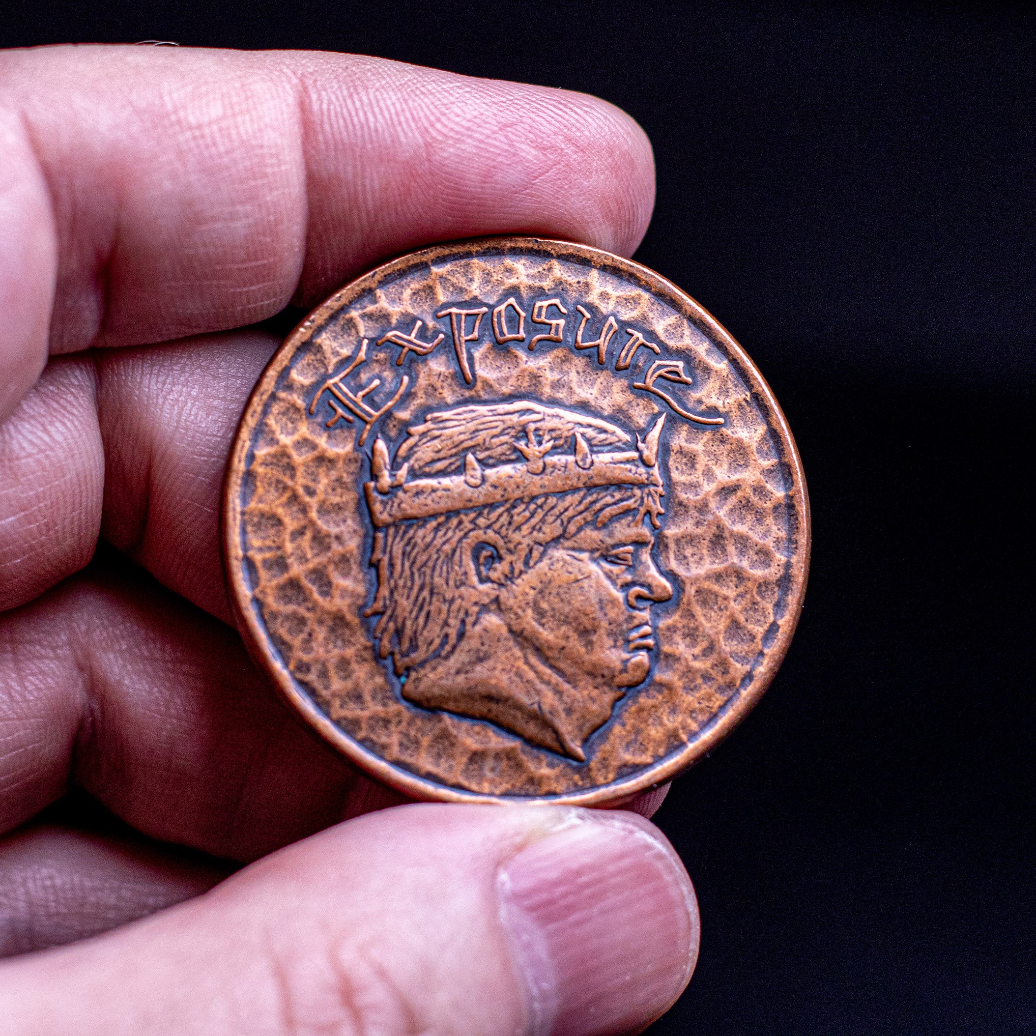 Hand holding copper Exposure Coin, showing the crowned king 
