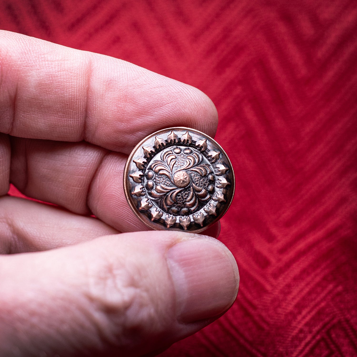 Thick copper worry coin featuring an intricate floral design
