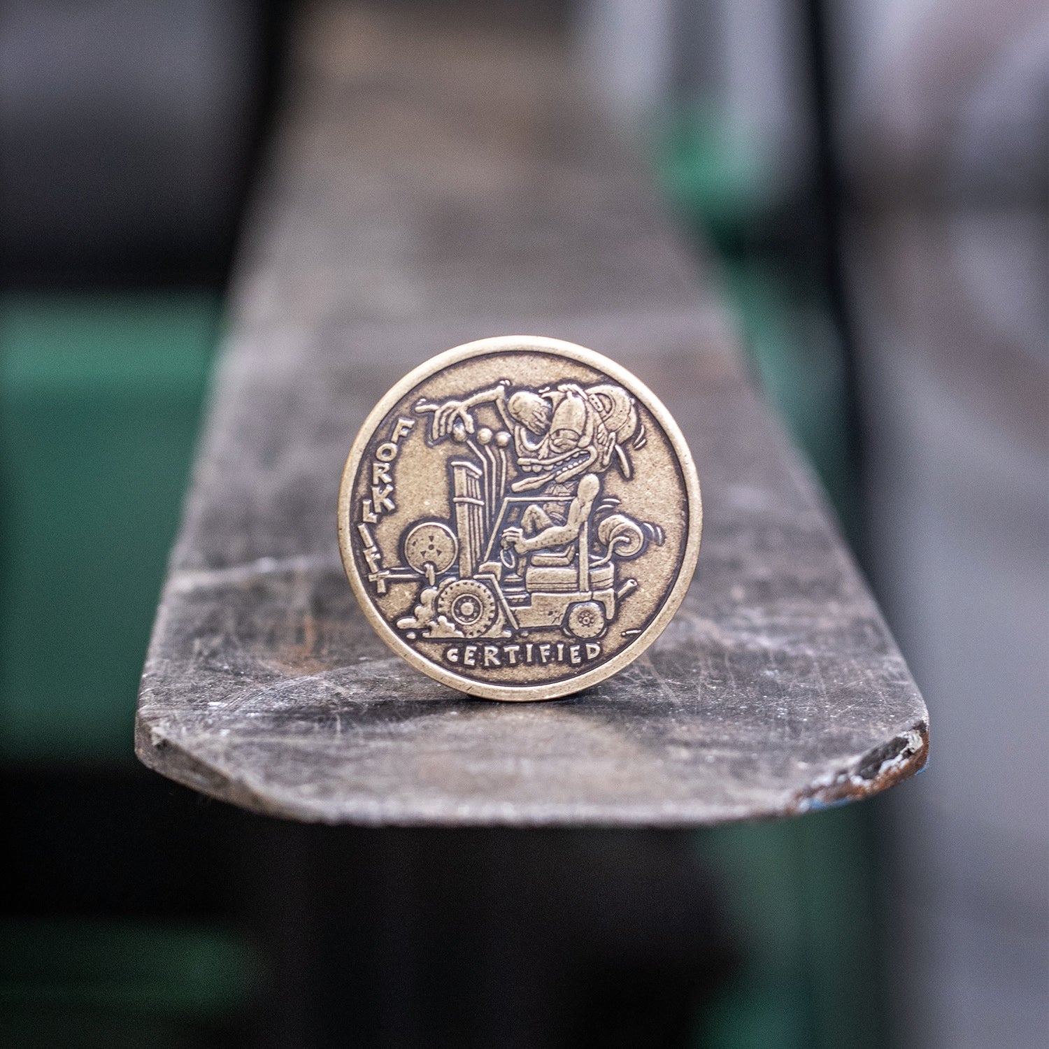 Brass coin depicting Forklift Certified cartoonish figure operating a forklift 