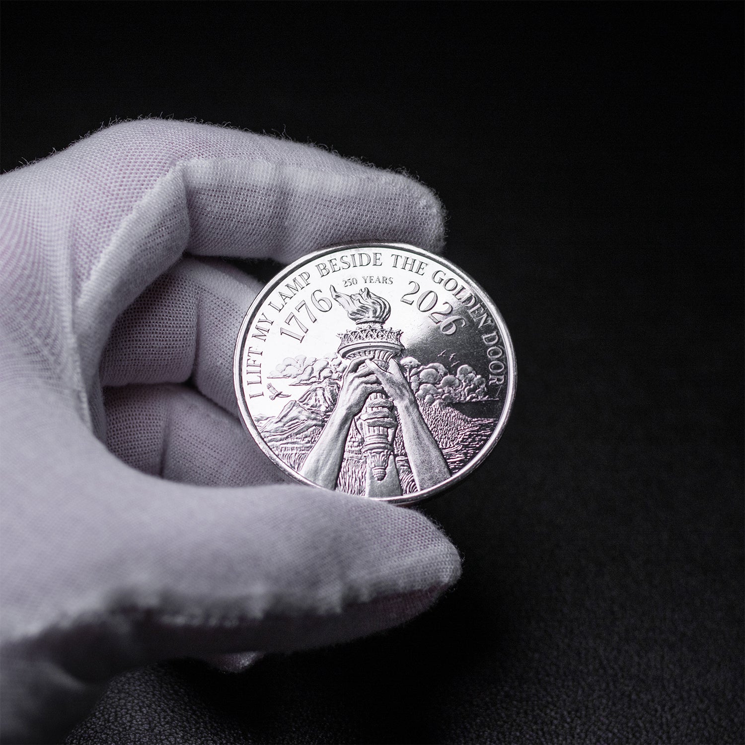 Gloved hand holding the silver coin's reverse side, set against a black background