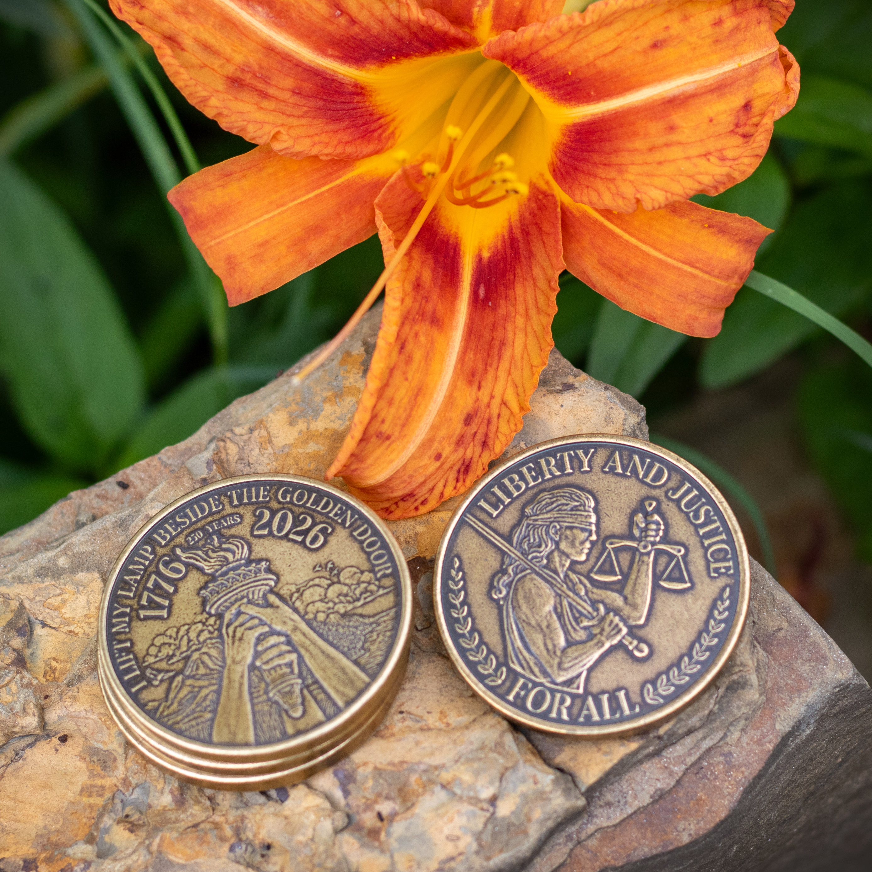 Stack of Liberty and Justice USA Anniversary Coins next to a bright, orange lily 